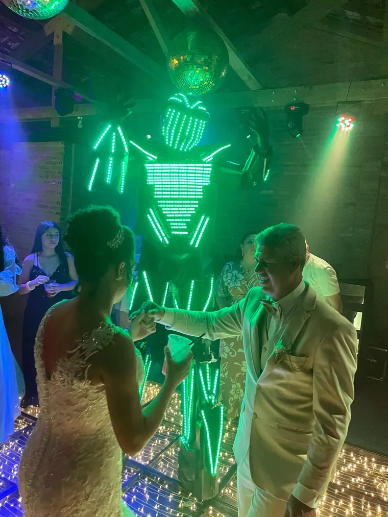 Noivos dançando ao lado do robô de LED verde